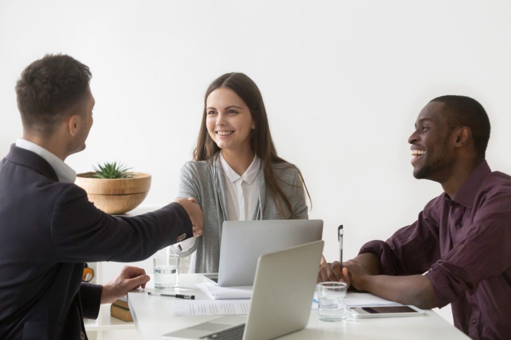 smiling businesswoman shaking hand male partner group meeting group