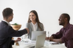 smiling-businesswoman-shaking-hand-male-partner-group-meeting-group